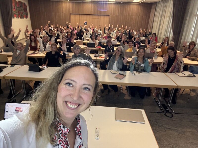 A full seminar room of participants with hands raised during a Werchota Advisory session
